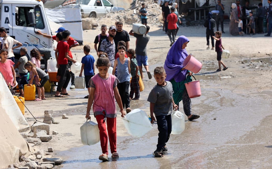 Palestinian children carry gallons of clean water from a distribution point in Gaza City.