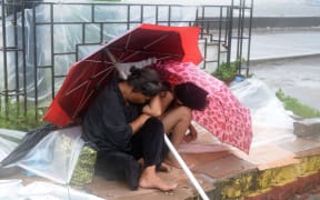 A mother shelters with her son from the wind and rain brought on by typhoon Koppu along Roxas boulevard in Manila.