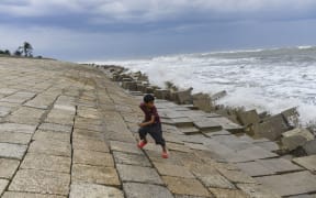A boy tries to escape from a wave at Shahpori island in Teknaf ahead of Cyclone Mocha's landfall in Cox's Bazar, Bangladesh on May 13, 2023. Bangladesh has raised the cyclone warning signal to 10 for Cox's Bazar and Teknaf areas.