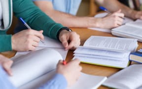 people, learning, education and school concept - close up of students hands with books or textbooks writing to notebooks