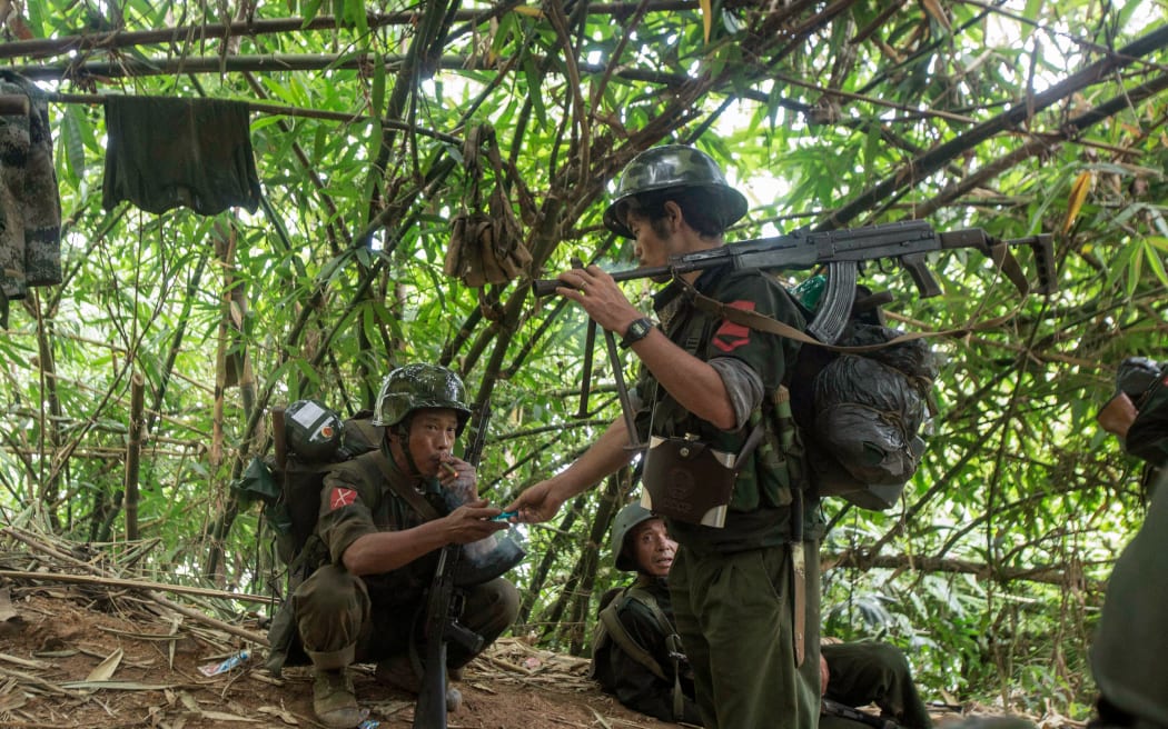 In this photograph taken October 14, 2016, armed rebels belonging to the Kachin Independence Army (KIA) ethnic group take a cigarette break as they move towards the frontline near Laiza in Kachin state. KIA rebels said they seized 20 government firearms, hundreds of rounds of ammunition and recovered bodies of four soldiers during the two days of fighting in mid-October. Renewed fighting has raged since November 20 between the Myanmar military and four armed ethnic groups, including the KIA. (Photo by Hkun Lat / AFP)