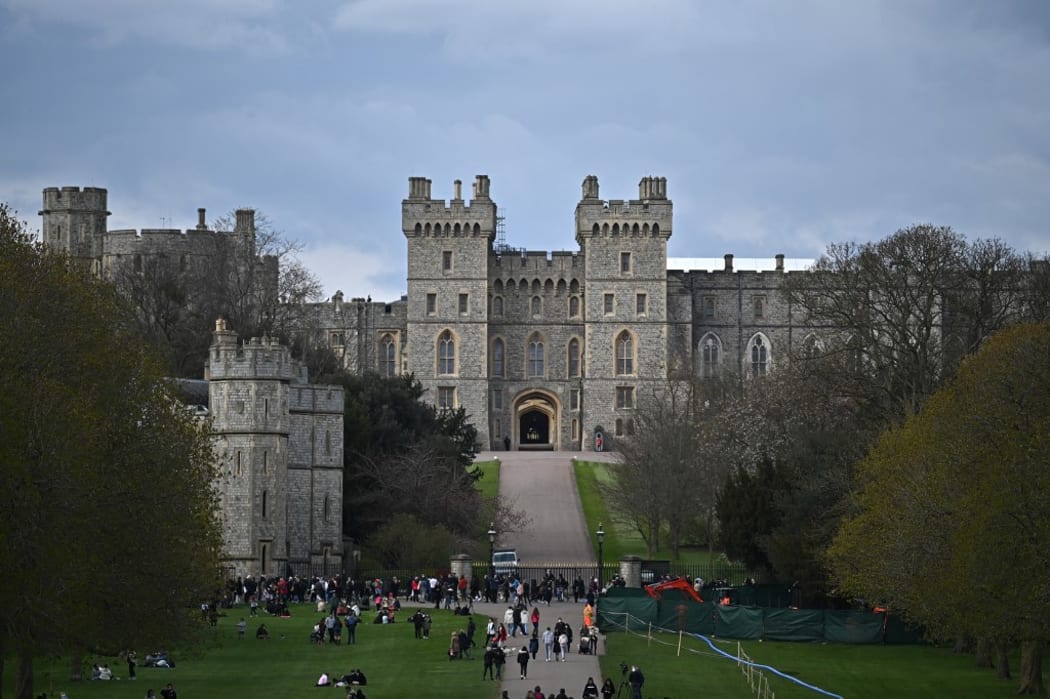 People walk through Windsor Great Park along the Long Walk with Windsor Castle in the background, in Windsor, west of London, on April 9, 2021, following the announcement of the death of Britain's Prince Philip, Duke of Edinburgh.