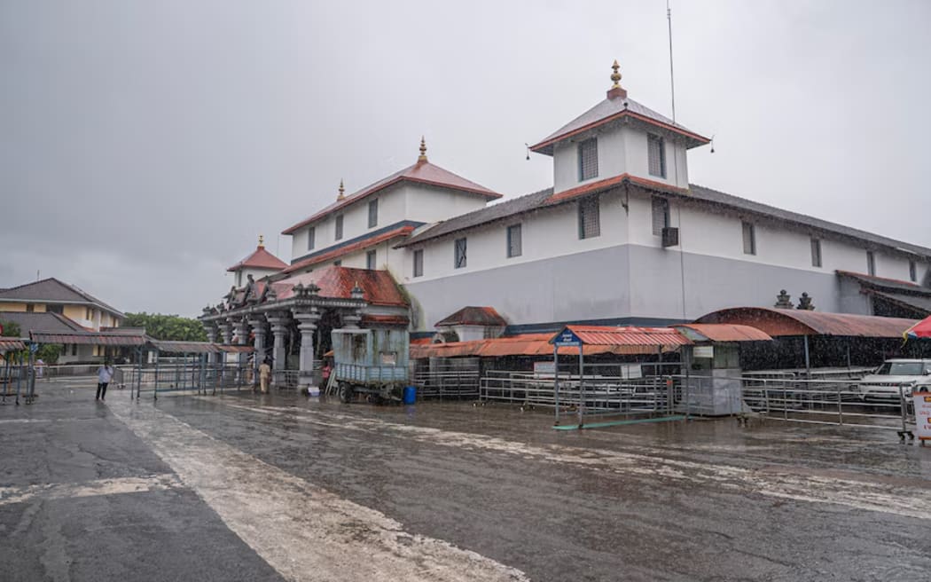 The exterior of a white, grey and red painted temple building on an overcast day.
