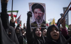 A veiled Iranian demonstrator holds a portrait of Iran's Supreme Leader Ayatollah Mojtaba Khamenei while participating in a pro-government rally commemorating Iran's female fighters, known as the country's self-sacrificing daughters, ahead of a military parade in southern Tehran, Iran, on April 17, 2026. The event takes place during a fragile ceasefire between Iran and the United States-Israeli coalition. (Photo by Morteza Nikoubazl/NurPhoto) (Photo by Morteza Nikoubazl / NurPhoto via AFP)