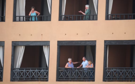Tourists stand on the balconies of their rooms at a hotel in Tenerife, in Spain's Canary Islands. Hundreds of people were confined to their rooms after an Italian tourist was hospitalised with a suspected case of coronavirus.