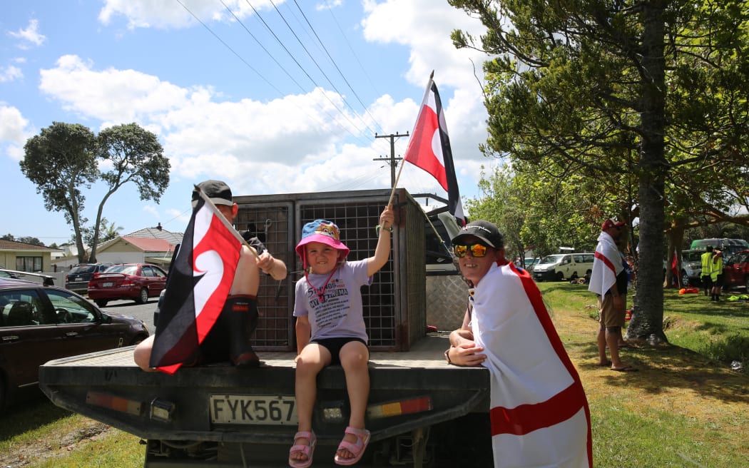 The Little whanau hold flags off the back of their ute as the hīkoi prepares to match through Dargaville.