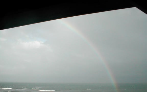 rainbow in grey clouds over sea