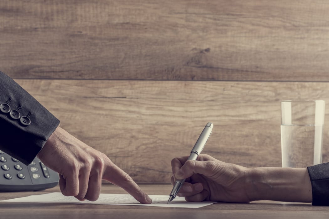 Closeup of employer showing his employee where to sign a contract, with a retro filter effect.