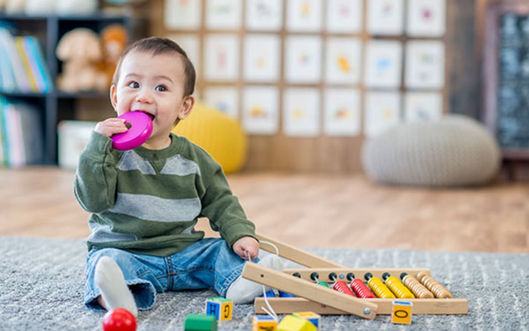 toddler with toy in mouth