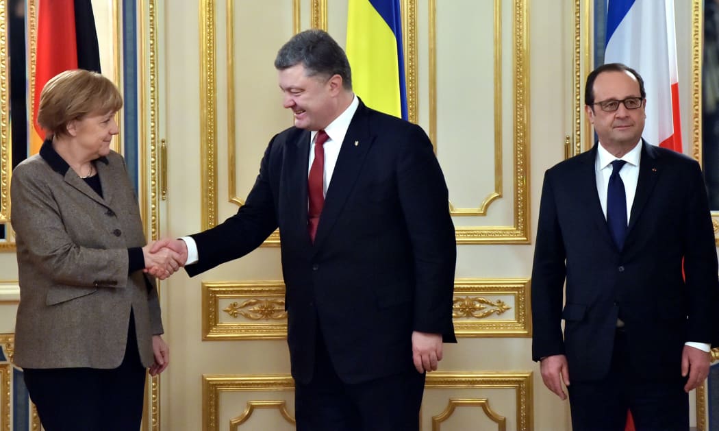 Ukrainian President Petro Poroshenko (C) shakes hands with German Chancellor Angela Merkel (L). French President Francois Hollande is on the right.