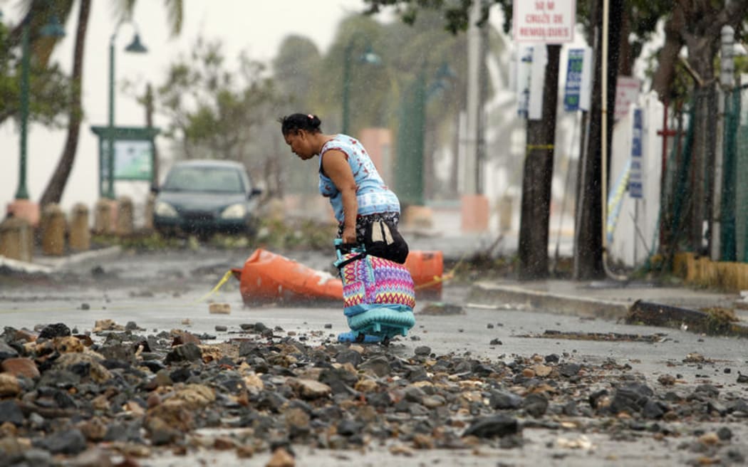 A woman pulls a travel case on a rock scattered road in the aftermath of Hurricane Irma in Fajardo, Puerto Rico.