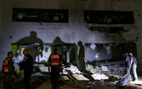 Members of Israel's Home Front Command and police forces inspect a crater left by an exploded projectile at a heavily-damaged school building in Israel's southern city of Gedera on October 1, 2024, after Iran launched a barrage of missiles at Israel in response to the killings of Lebanese Hezbollah leader Nasrallah and other Iran-backed militants. Reports said Iran fired between 150 and 200 missiles in the attack, the country's second on Israel after a missile and drone attack in April in response to a deadly Israeli air strike on the Iranian consulate in Damascus. (Photo by Menahem KAHANA / AFP)
