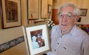 Patrick Nolan hold a photo of him meeting Queen Elizabeth II during his time in London.