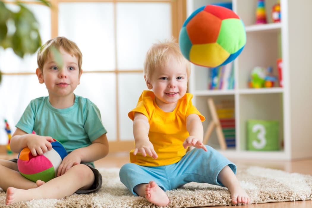 A photo of two toddlers playing with balls