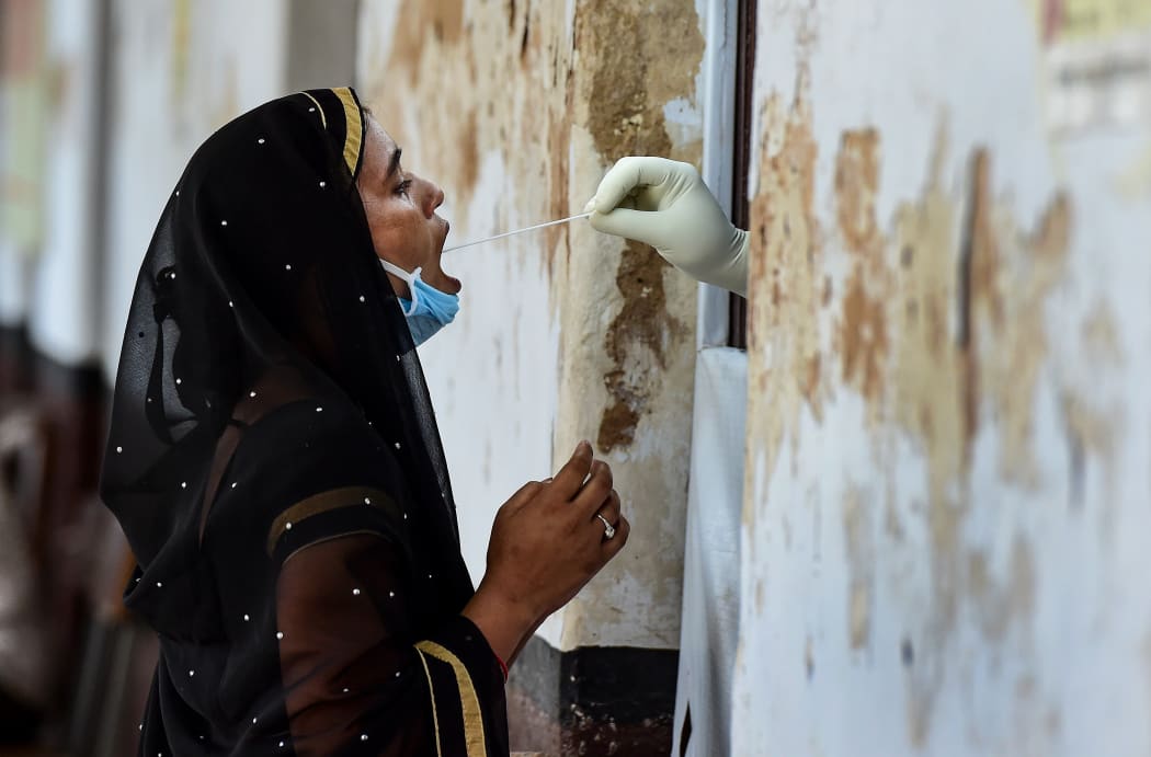 A health official takes a swab sample from a woman to test for the Covid-19 coronavirus at a testing point in Allahabad, India