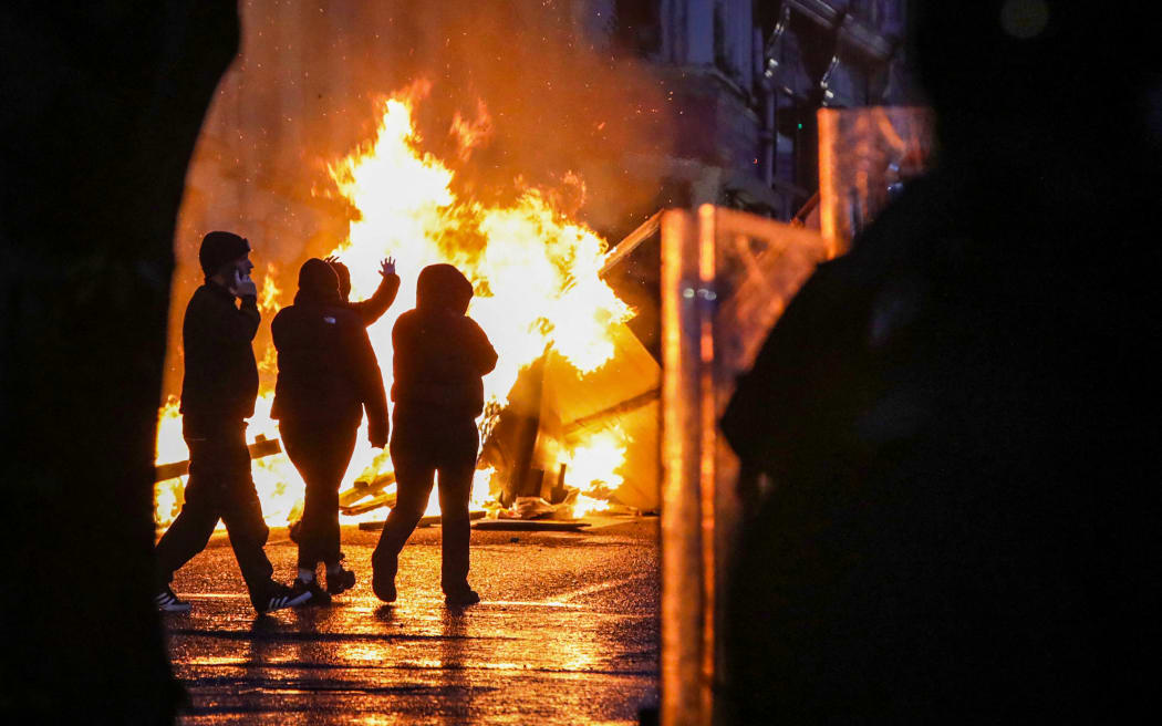Protestors walk past a fire lit in a street of Ballymena, Northern Ireland, during an anti-immigration demonstration.