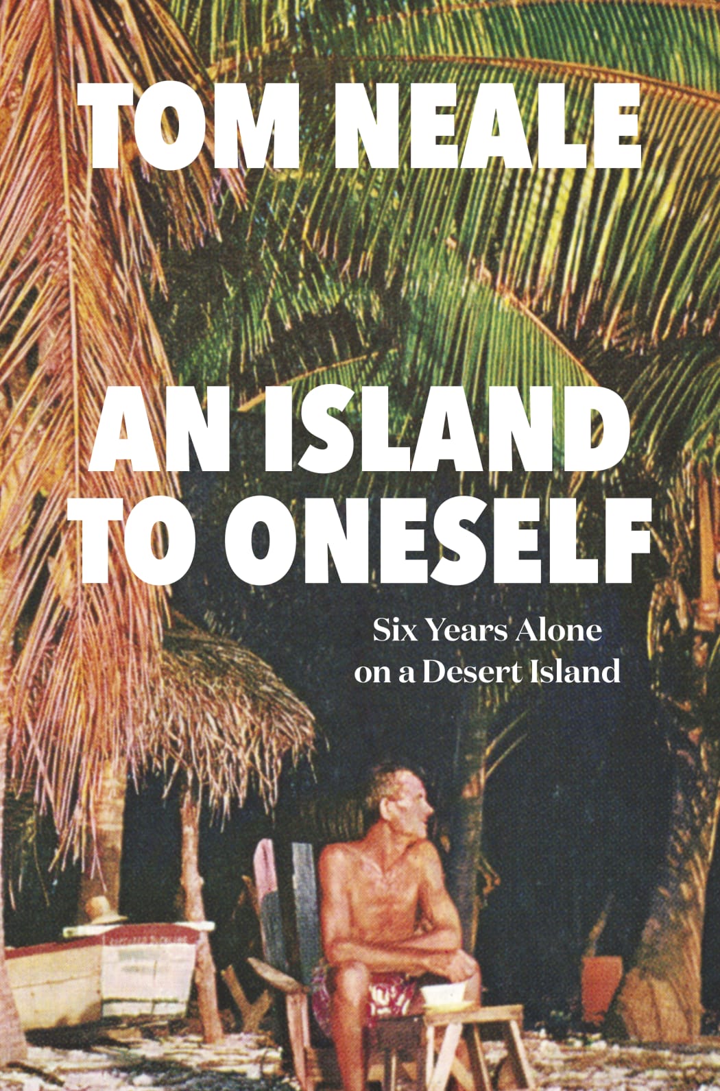 The cover of "AN ISLAND TO ONESELF". A photo of Tom Neale sitting on a deck chair on a beautiful deserted island.