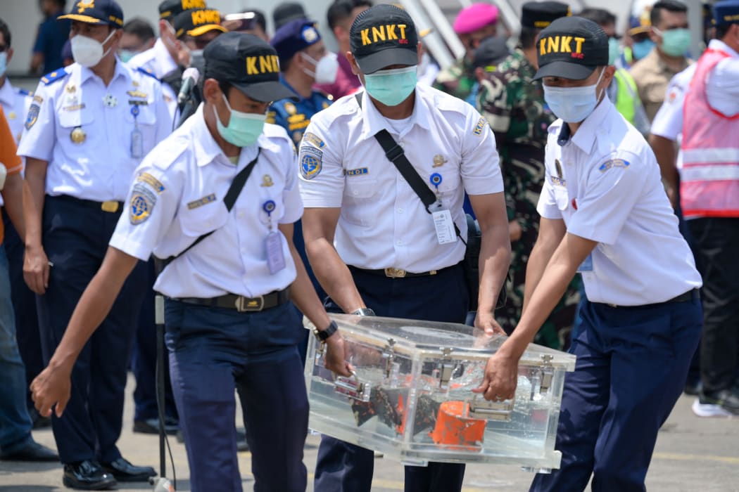 Indonesian officials carry a box contain cockpit voice recorder (CVR or blackbox) on March 31, 2021 after it was recovered during search operations for the Sriwijaya Air Boeing 737-500 passenger jet.