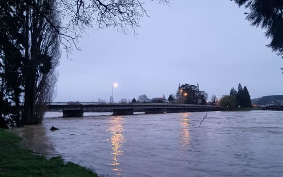 The Mataura River at Gore is flowing swiftly and some debris is caught under a rail bridge.
