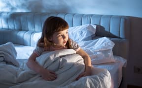 A photo of a girl of 4 years at night time who looks afraid to go to sleep