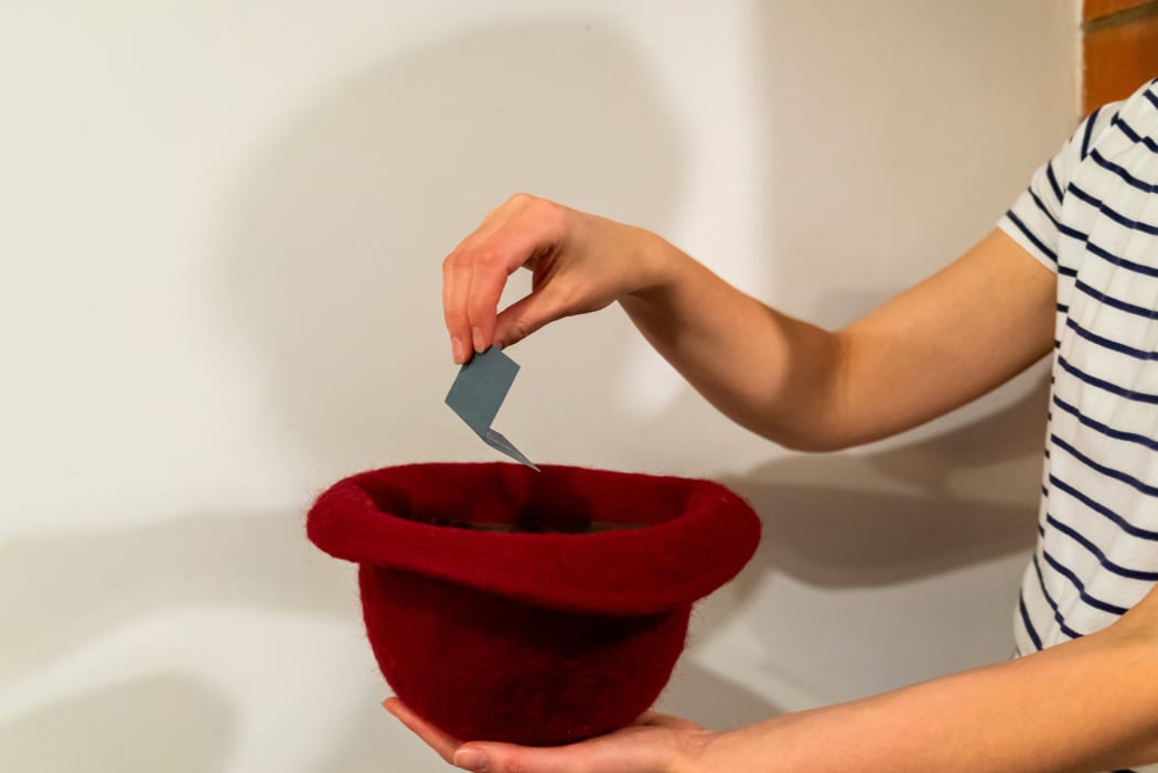 Woman's hand drawing a card with a name from hat. (File picture)