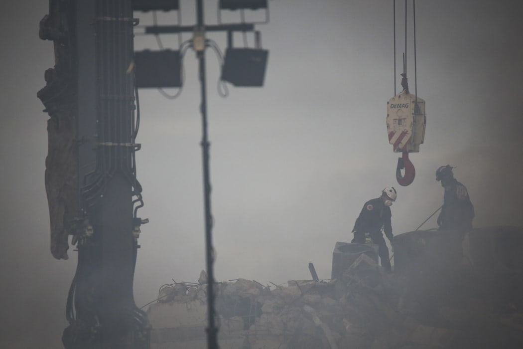 Rescue workers look for possible survivors among the debris of a partially collapsed building