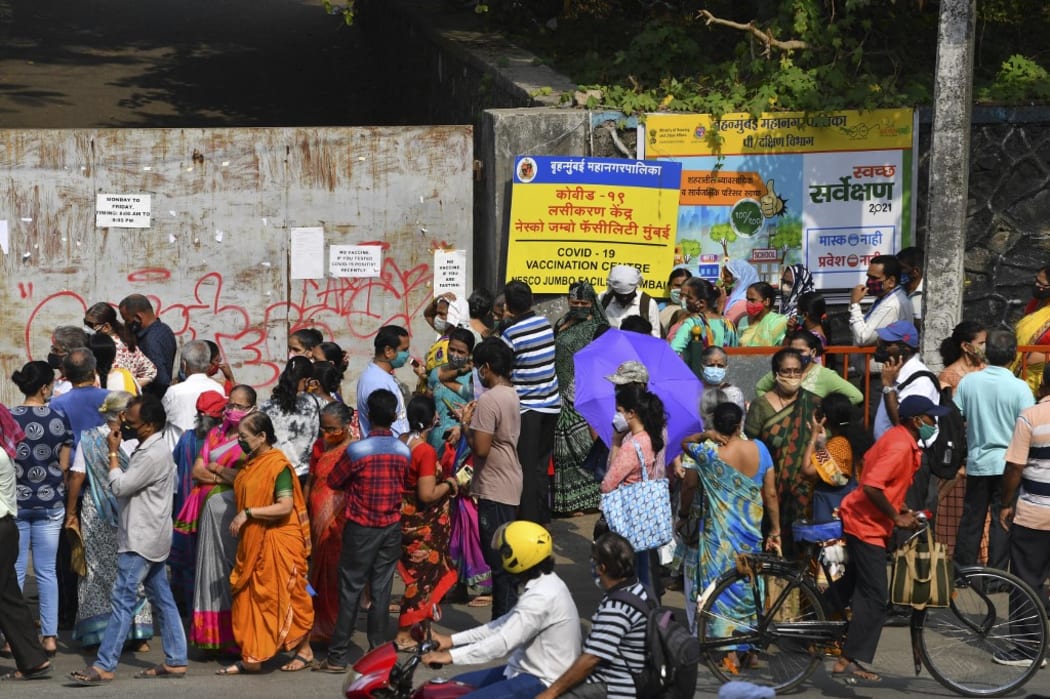 People gather outside an entrance gate of a Covid-19 coronavirus vaccination centre in Mumbai on April 28, 2021. (Photo by INDRANIL MUKHERJEE / AFP)
