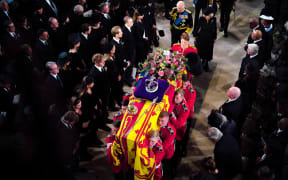 The Bearer Party of The Queen's Company, 1st Battalion Grenadier Guards carry the coffin of Queen Elizabeth II, draped in a Royal Standard and adorned with the Imperial State Crown and the Sovereign's orb and sceptre, inside St George's Chapel at Windsor Castle at the Committal Service on 19 September 2022.