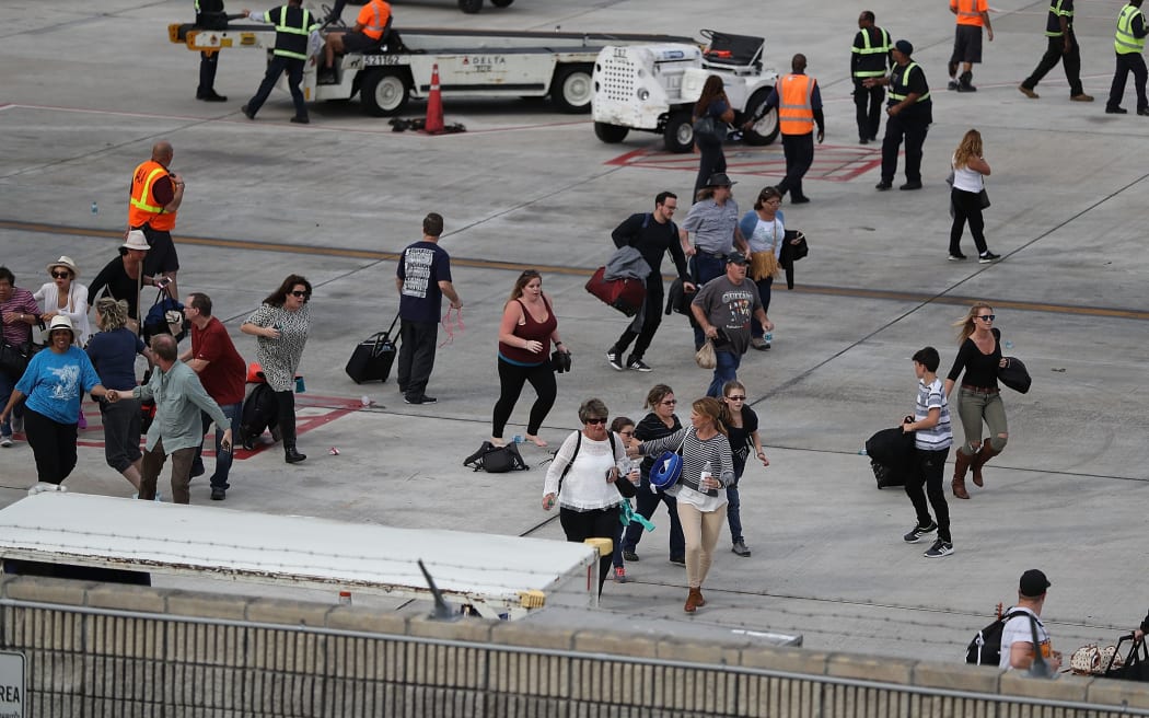 People seek cover on the tarmac of Fort Lauderdale-Hollywood International airport after a shooting took place near the baggage claim.