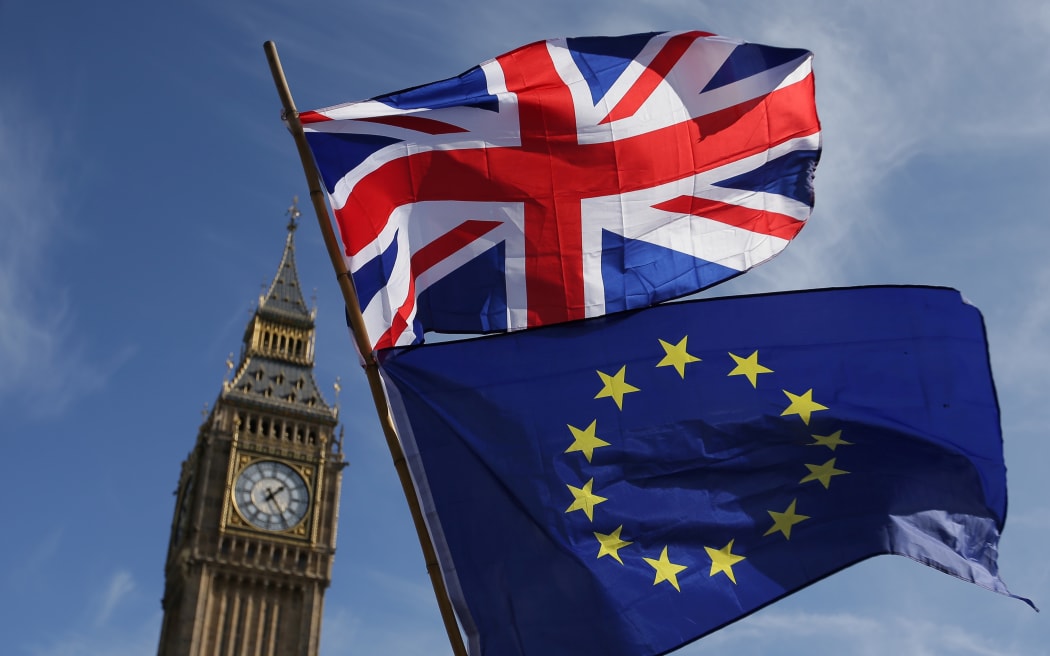 (FILES) In this file photo taken on March 25, 2017 an EU flag and a Union flag held by a demonstrator is seen with Elizabeth Tower (Big Ben) and the Houses of Parliament as marchers taking part in an anti-Brexit, pro-European Union (EU) enter Parliament Square in central London.