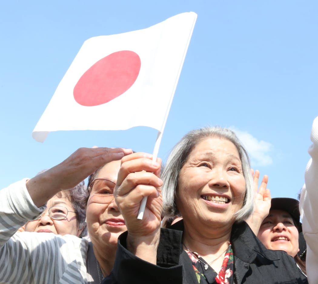 A woman waves Japan's national flag during Japan's new Emperor Naruhito's public appearance at the Imperial Palace in Tokyo on May 4, 2019.