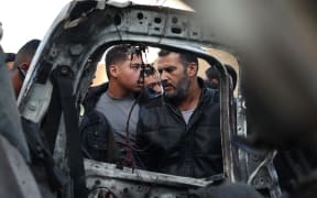 People gather around the carcass of a Palestinian police vehicle that was reportedly destroyed in Israeli bombardment in Rafah in the southern Gaza Strip on February 10, 2024, amid the ongoing conflict between Israel and the Palestinian Hamas militant group. (Photo by SAID KHATIB / AFP)