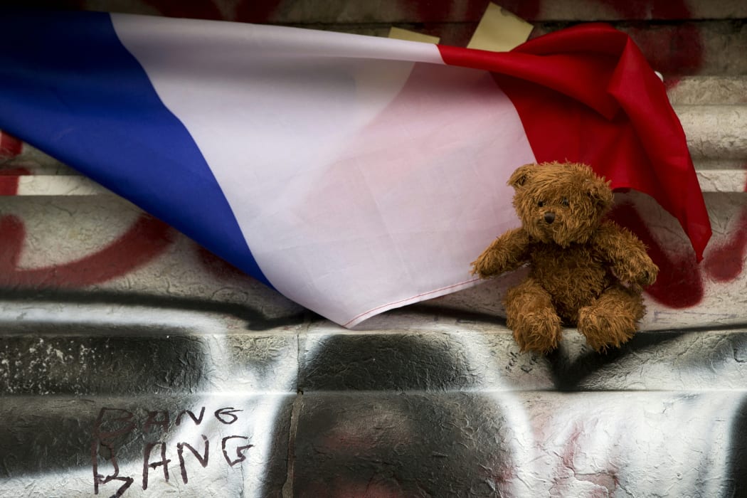 A picture taken on December 2, 2015 in Paris shows a cuddly toy and a French flag at a makeshift memorial in front of the statue of the Republique in tribute to the victims of November 13 terror attacks in Paris.
