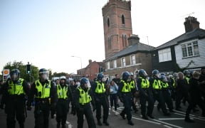 Riot police follow a march into the town centre of Epping, northest of London, on July 20, 2025 from a demonstration outside The Bell Hotel, believed to be housing asylum seekers after police charged an asylum-seeker with sexual offences earlier this month.  (Photo by JUSTIN TALLIS / AFP)