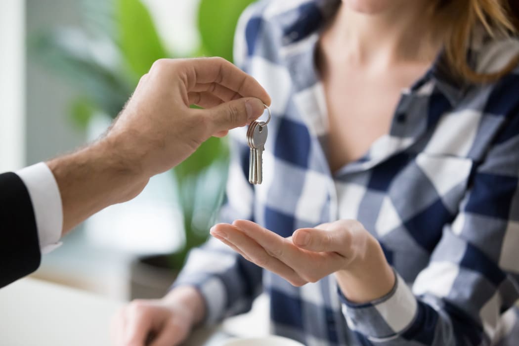 Young woman getting keys to new apartment from realtor. Family buys, rents new house. Customers or renters buy or rent real estate, close up