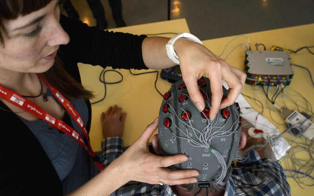 Physiotherapist Vanessa Buhlmann places electrodes on the head of patient Jean-Francois Vernetti during a presentation of a brain-machine interface by the Swiss Federal Institutes of Technology of Lausanne (EPFL) on January 23, 2013 in Sion.