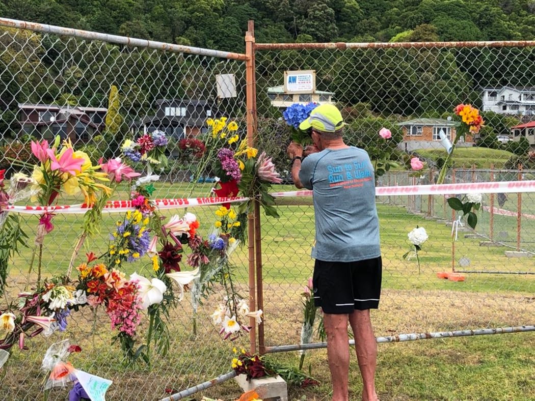 A local man places flowers from his garden on the Whakatāne boat ramp cordon.