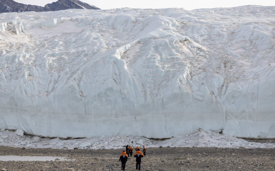 Prime Minister Jacinda Ardern and her partner Clarke Gayford walk towards the rest of their party standing in front of a glacier in the Taylor Valley - one of Antarctica's iconic dry valleys - on 27 October, 2022.
