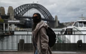 A woman walks past the Sydney Harbour Bridge after stay-at-home orders were lifted across NSW, in Sydney, Australia, Tuesday, October 12, 2021.