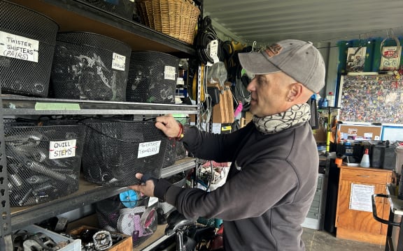 Picture of a man getting bike parts from a shelf.