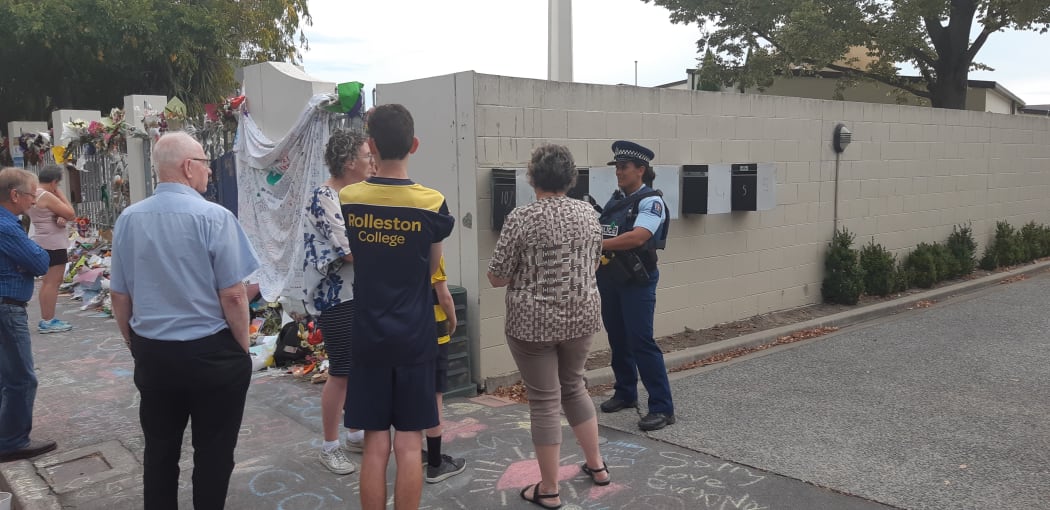 Police officers speak to onlookers at Al Noor Mosque.