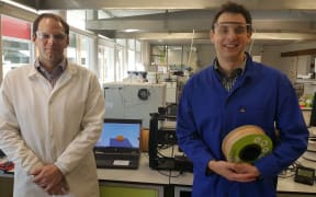 Marc Gaugler and Florian Graichen in front of 3D printing machines in the lab at Scion. Florian is holding a roll of wood-based bioplastic that can be used in the printers.