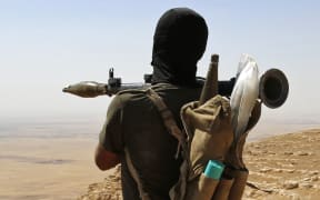 A Kurdish Peshmerga fighter overlooking a village near Mosul controlled by Islamic State.