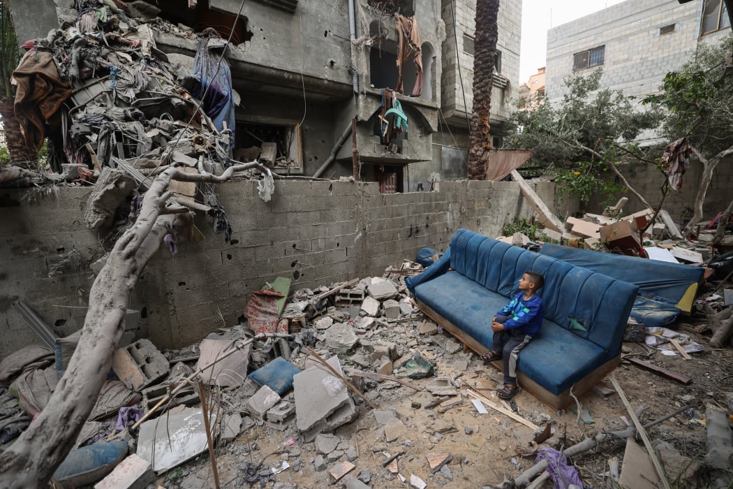 A Palestinian boy sits on a damaged couch as he watches people clearing the rubble from a house that was hit in Israeli strikes at the Nuseirat refugee camp in the central Gaza Strip on May 18, 2025. Gaza's civil defence spokesman Mahmud Bassal told AFP that 22 people were killed and at least 100 others wounded in a predawn attack on tents sheltering displaced Palestinians in Al-Mawasi, in the southern Gaza Strip.