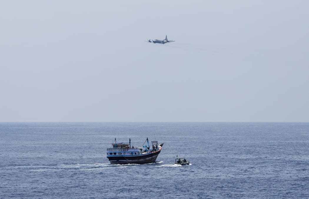 A Royal New Zealand Air Force P-3K2 Orion flies past HMAS Warramunga boarding team during an operation in the Western Indian Ocean.
