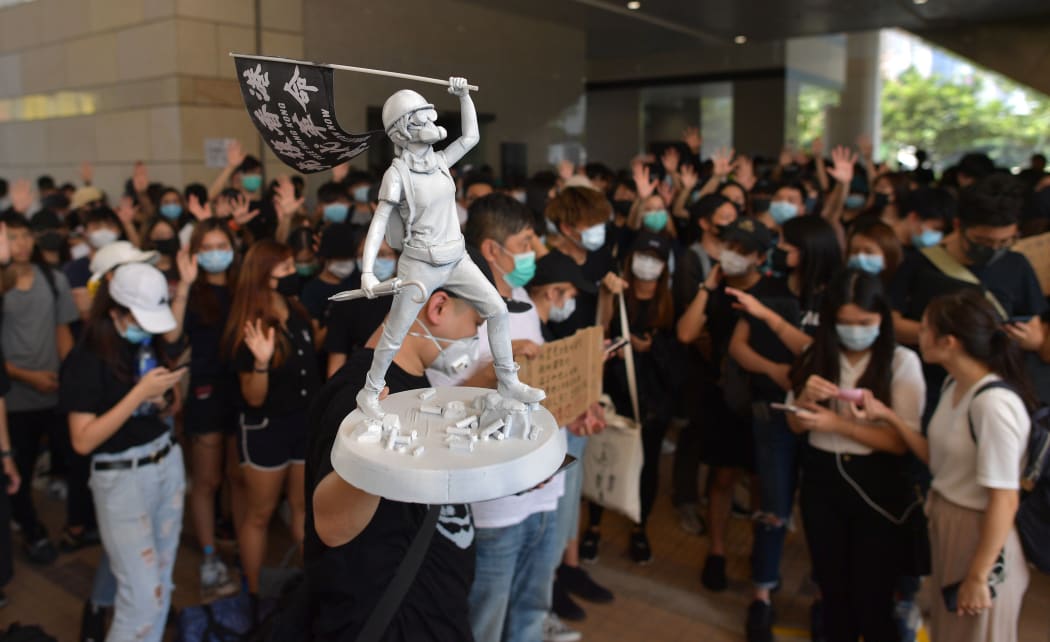 A man carries a miniature statue as protesters and supporters gather outside the entrance to the West Kowloon Court in Hong Kong on October 2, 2019, where some 96 protesters arrested and charged with rioting during clashes with police on September 29 were to make an appearance in court.