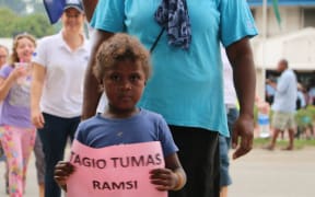 A boy hold a sign bearing the words "Thank you very much, RAMSI"