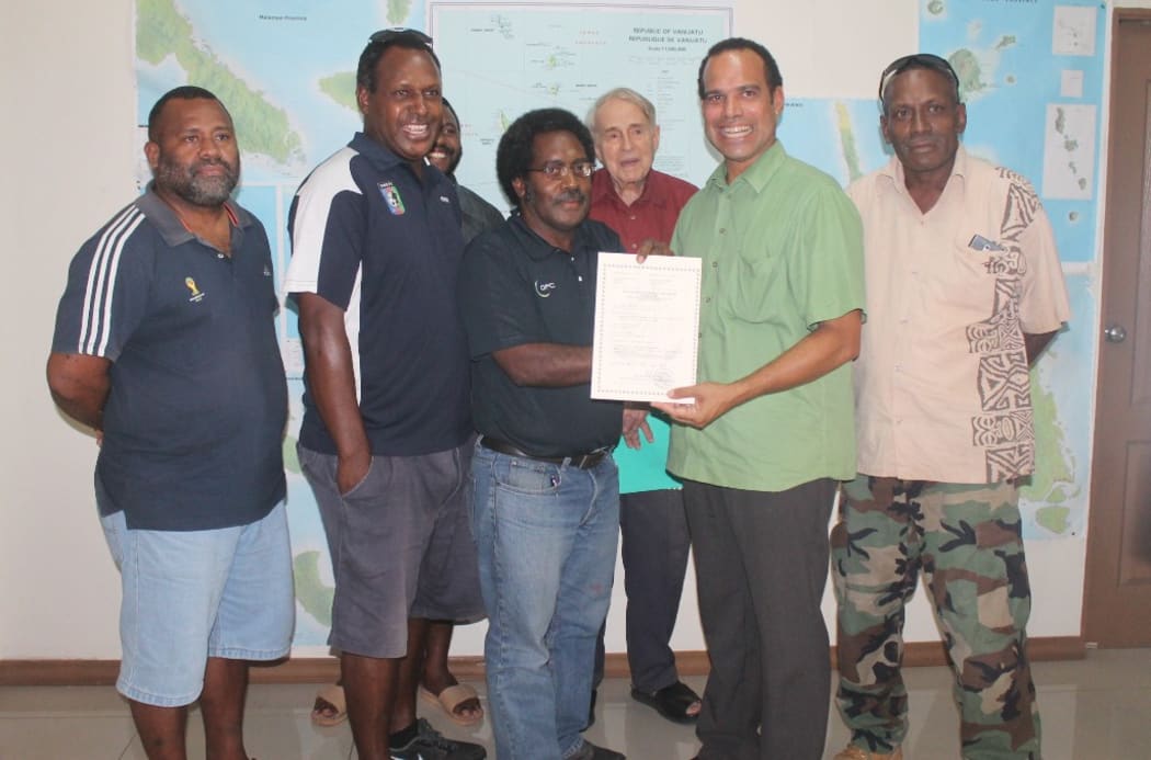 Vanuatu's Minister of Lands Ralph Regenvanu (green shirt) hands over the first negotiator's certificate to be issued for a lease application for rural customary land, to the Vanuatu Football Federation.