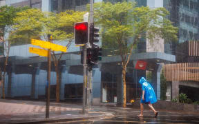 A man walks through the Central Business District (CBD) area of Brisbane on March 8, 2025, as cyclone Alfred crossed the southeast Queensland coast. Cyclone Alfred weakened into a tropical low on March 8 but still threatened to unleash major floods on swollen rivers as it approached the rain and wind-lashed eastern coast of Australia. (Photo by Patrick HAMILTON / AFP)