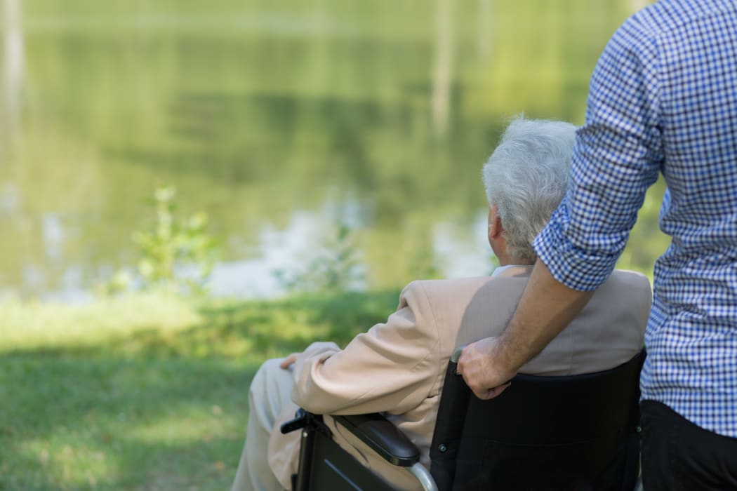 Photo of elderly man on wheelchair and his private carer